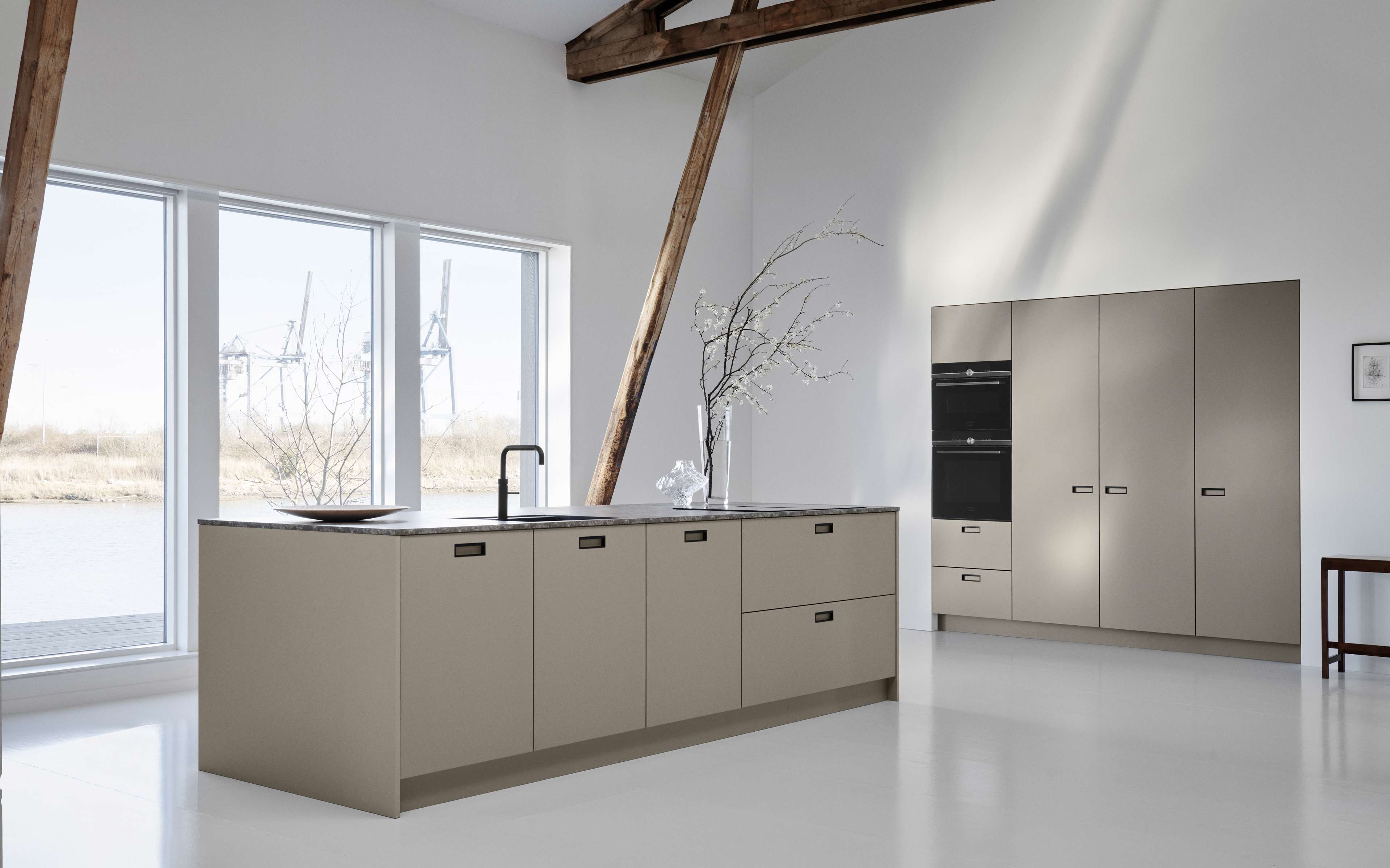 AVOLIA-Tonküche mit eleganten, minimalistischen Schränken und integrierten Geräten, die einen nahtlosen und eleganten Kochraum mit viel Stauraum schaffen.