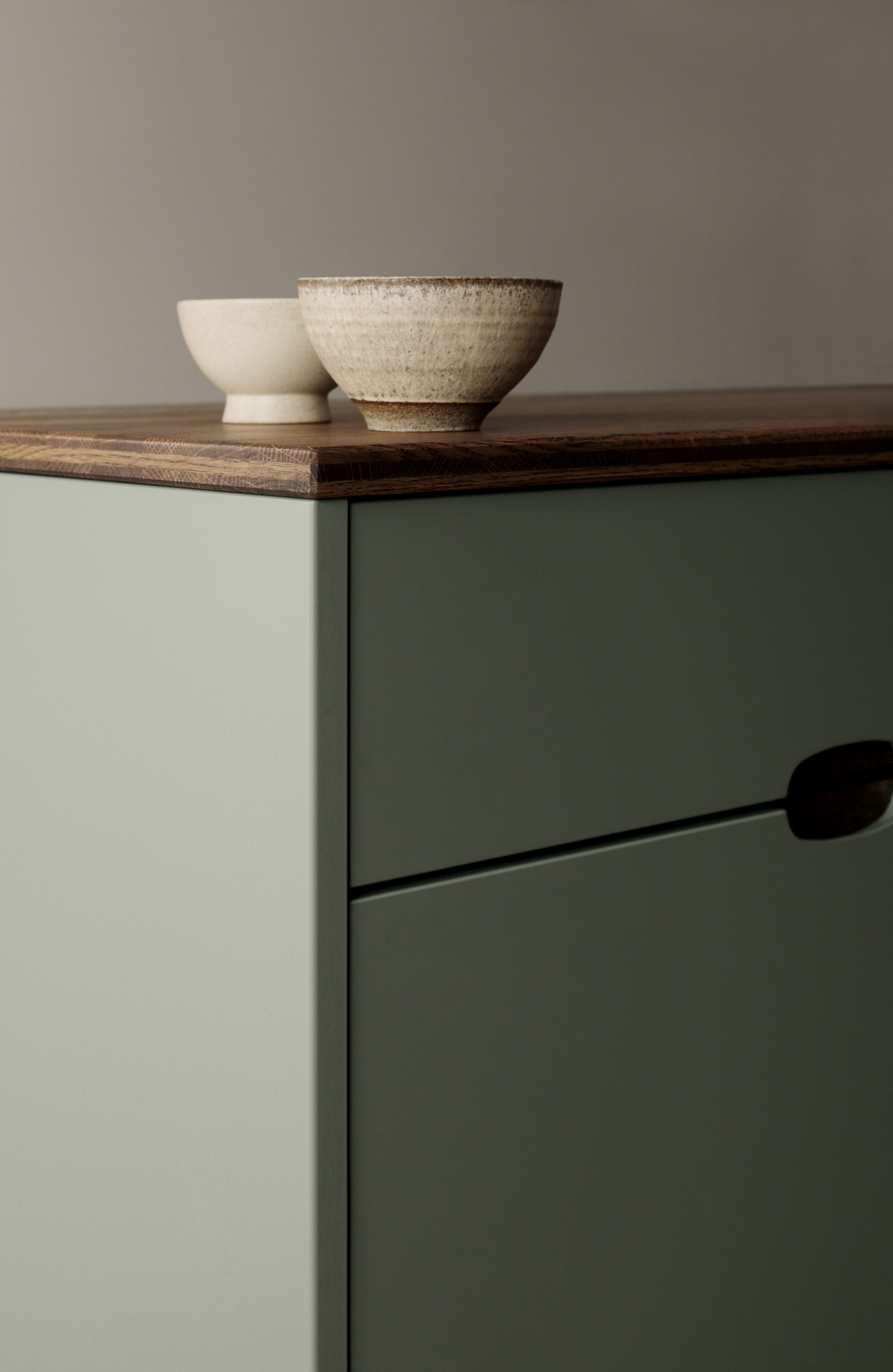 OMBRA green kitchen cabinet with sleek, minimalist design featuring smooth edges and rich wooden countertop for a stylish, modern kitchen space.