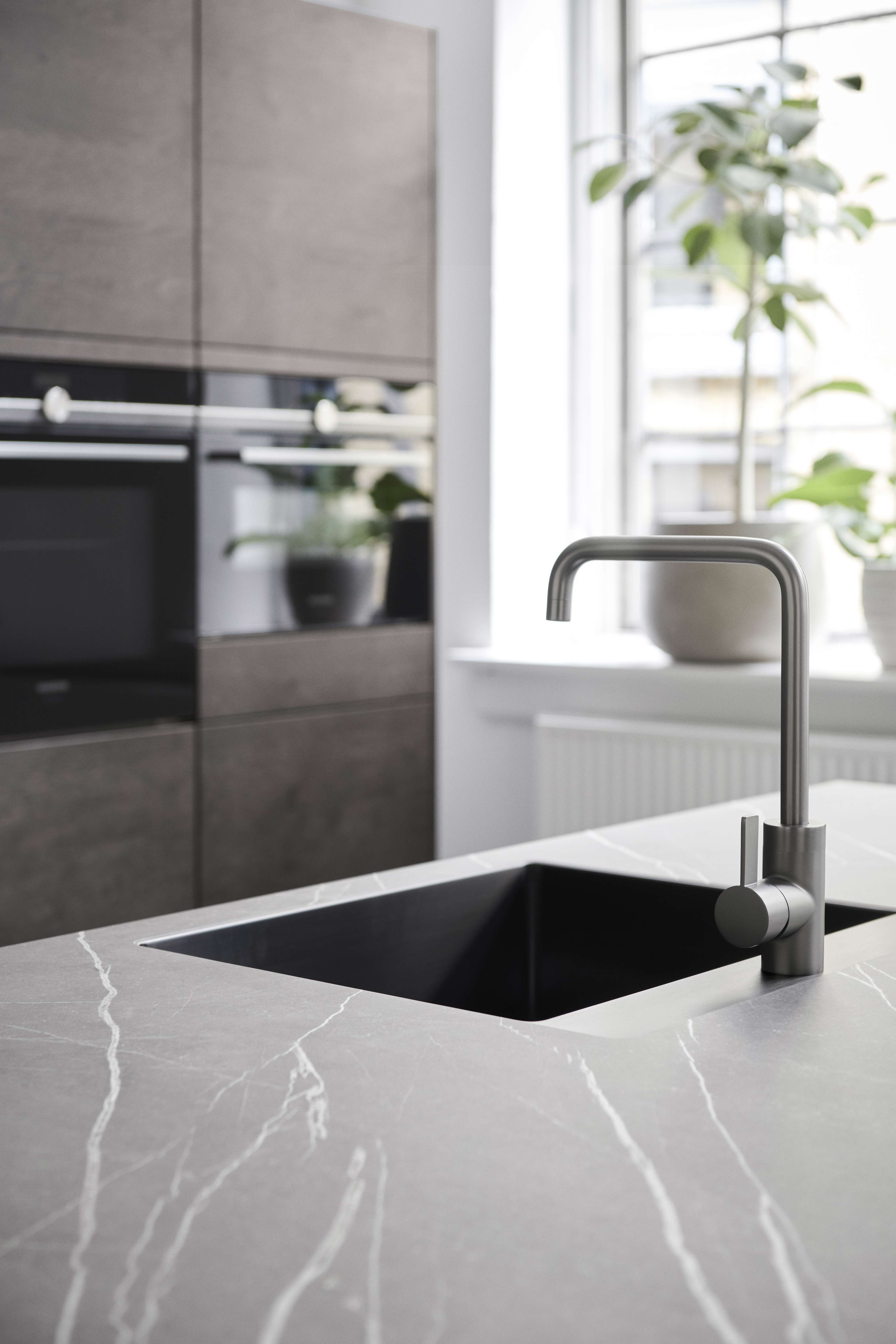 Cuisine VEDA Touch en chêne foncé gris pur avec comptoir en marbre élégant, équipements intégrés minimalistes et éléments de design scandinave moderne.
