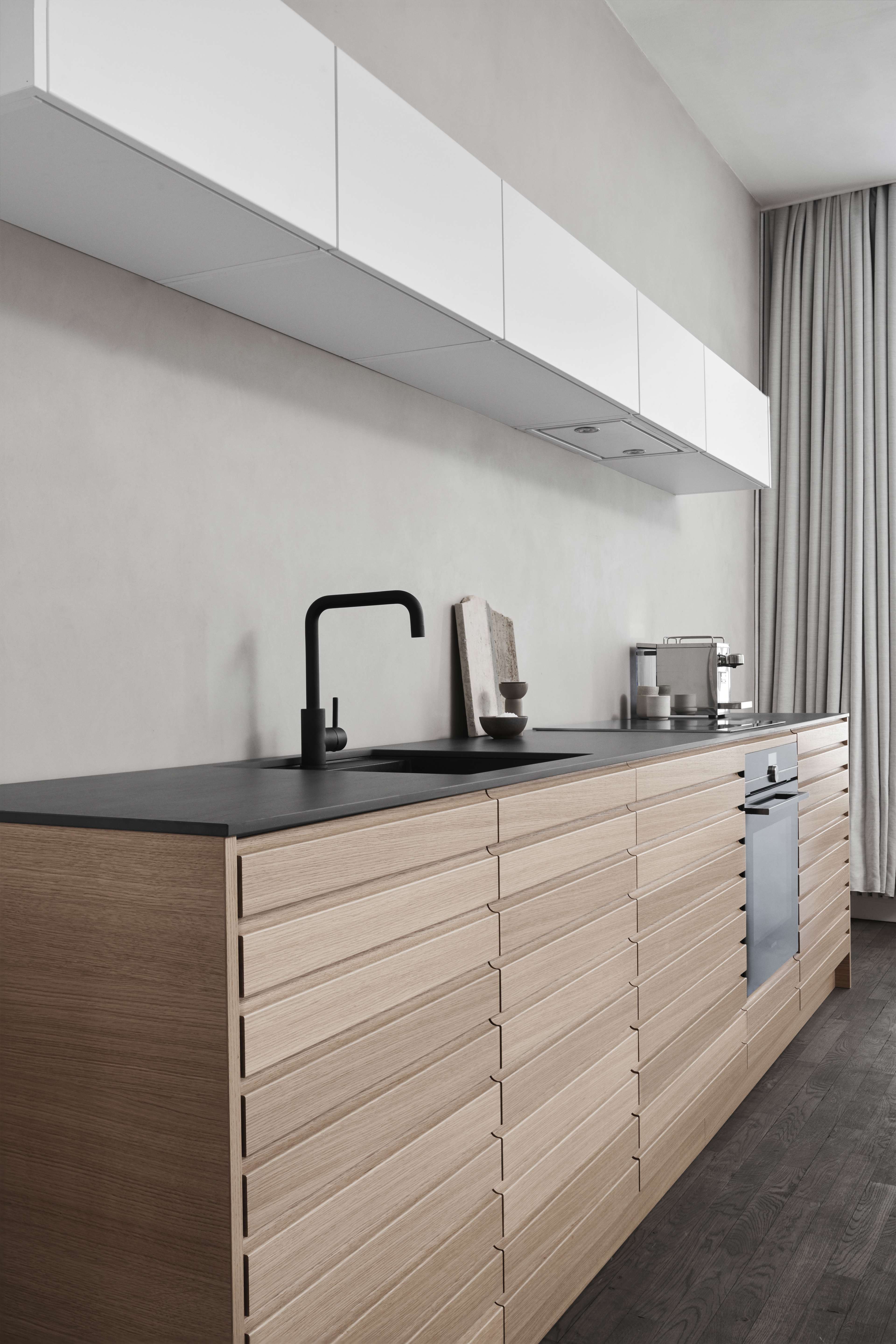 CIMA licht eiken keuken met horizontale lambrisering en strak zwart aanrechtblad, met een modern, minimalistisch ontwerp voor een elegante en functionele ruimte.