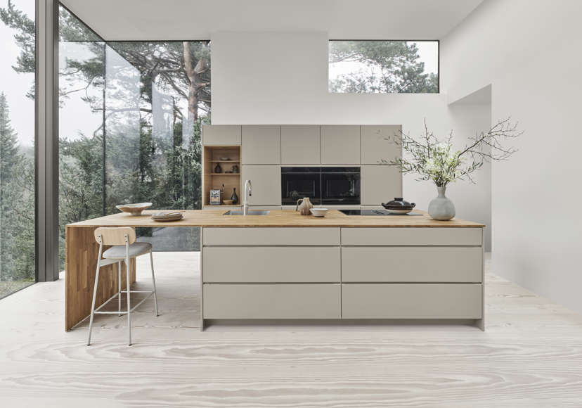 MANO arizona beige kjøkken viser minimalistisk eleganse med glatt kabinett og integrerte håndtak, forsterket av benkeplater i tre i rolige omgivelser.