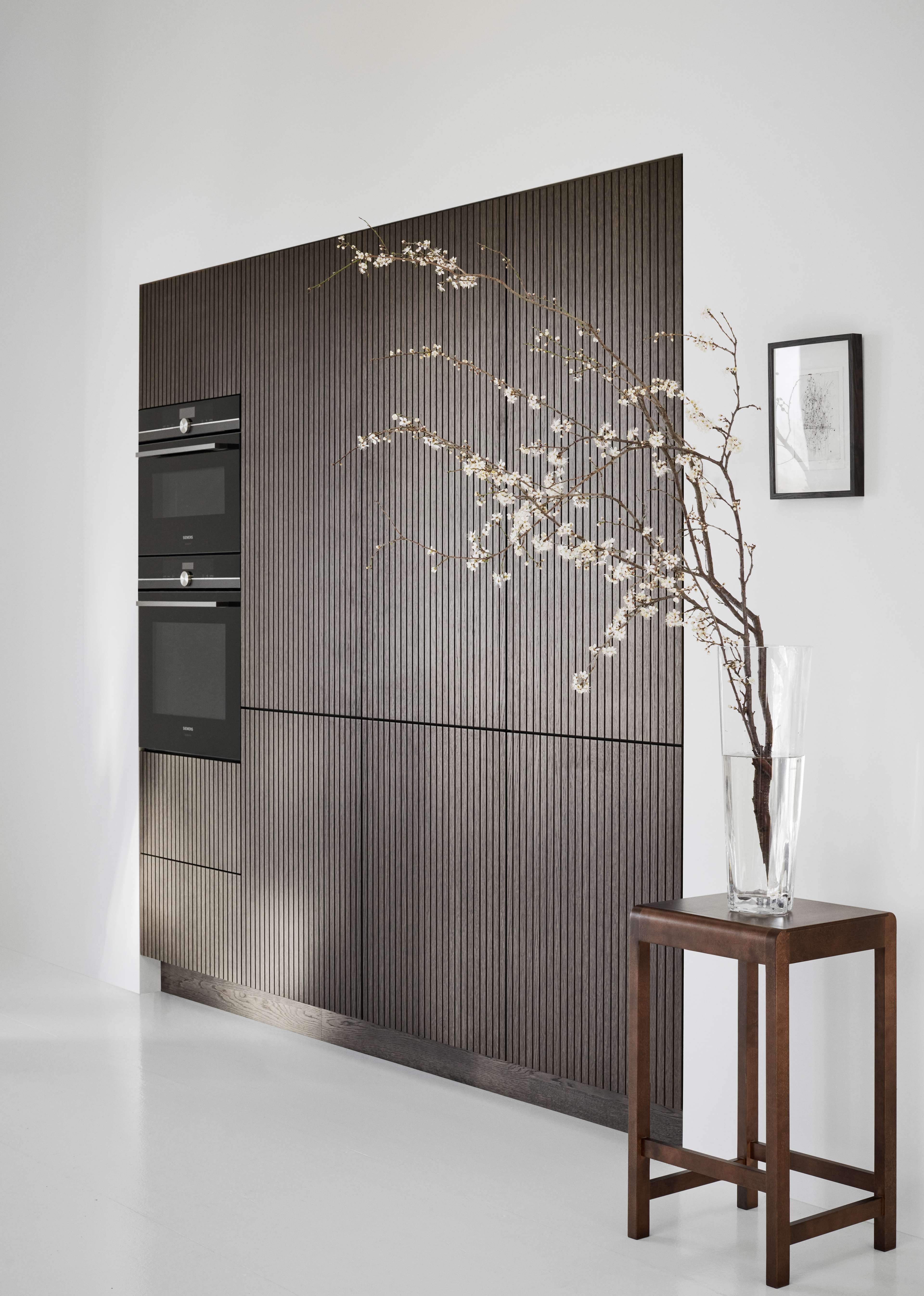 CORISA keukenkasten van donker eikenhout met verticale houten latten, die een moderne, minimalistische esthetiek naadloos combineren met functionele elegantie.