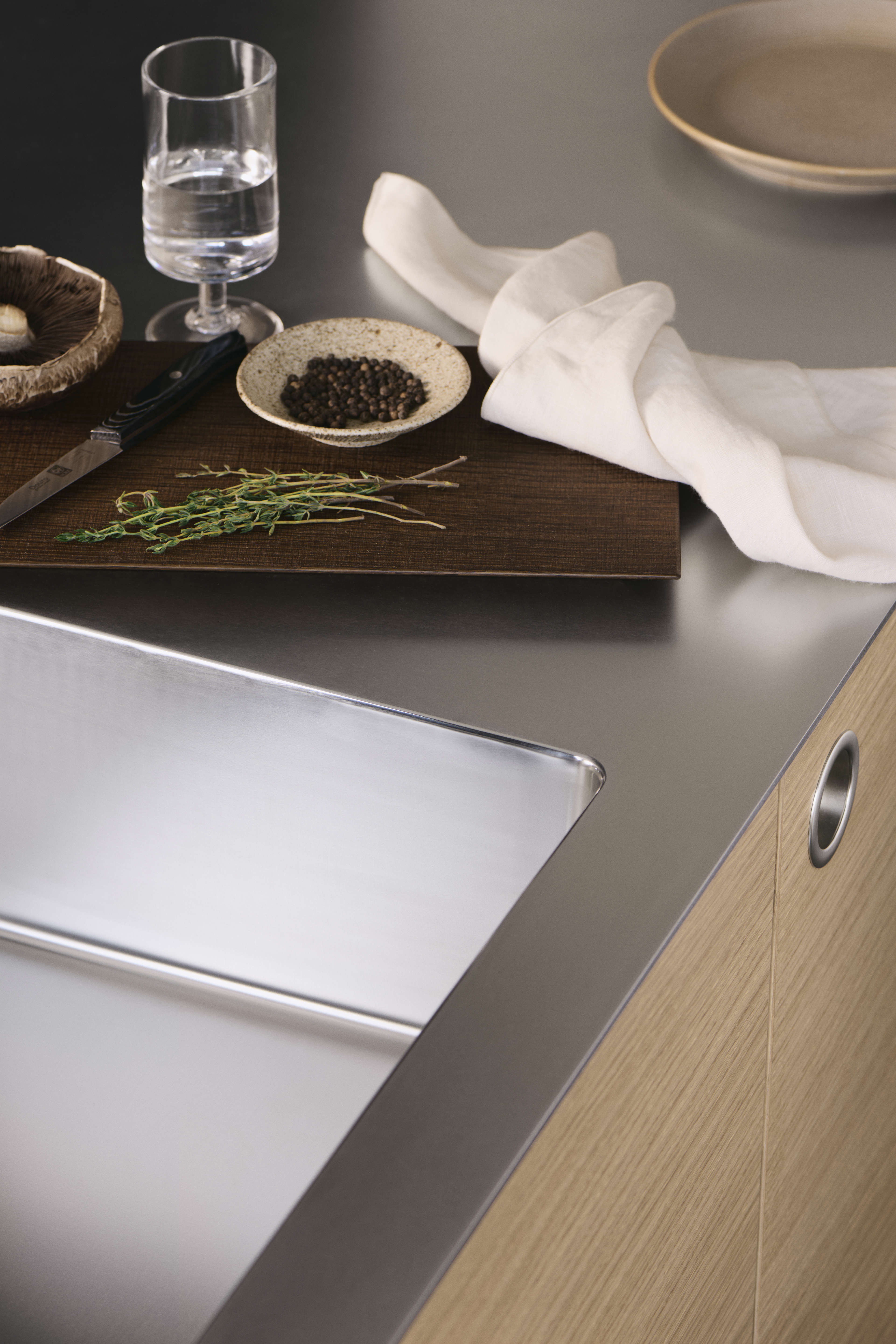 VEDA licht eiken keuken met strak roestvrijstalen aanrechtblad en geïntegreerde handgrepen, waarbij modern design wordt gecombineerd met praktische elegantie.