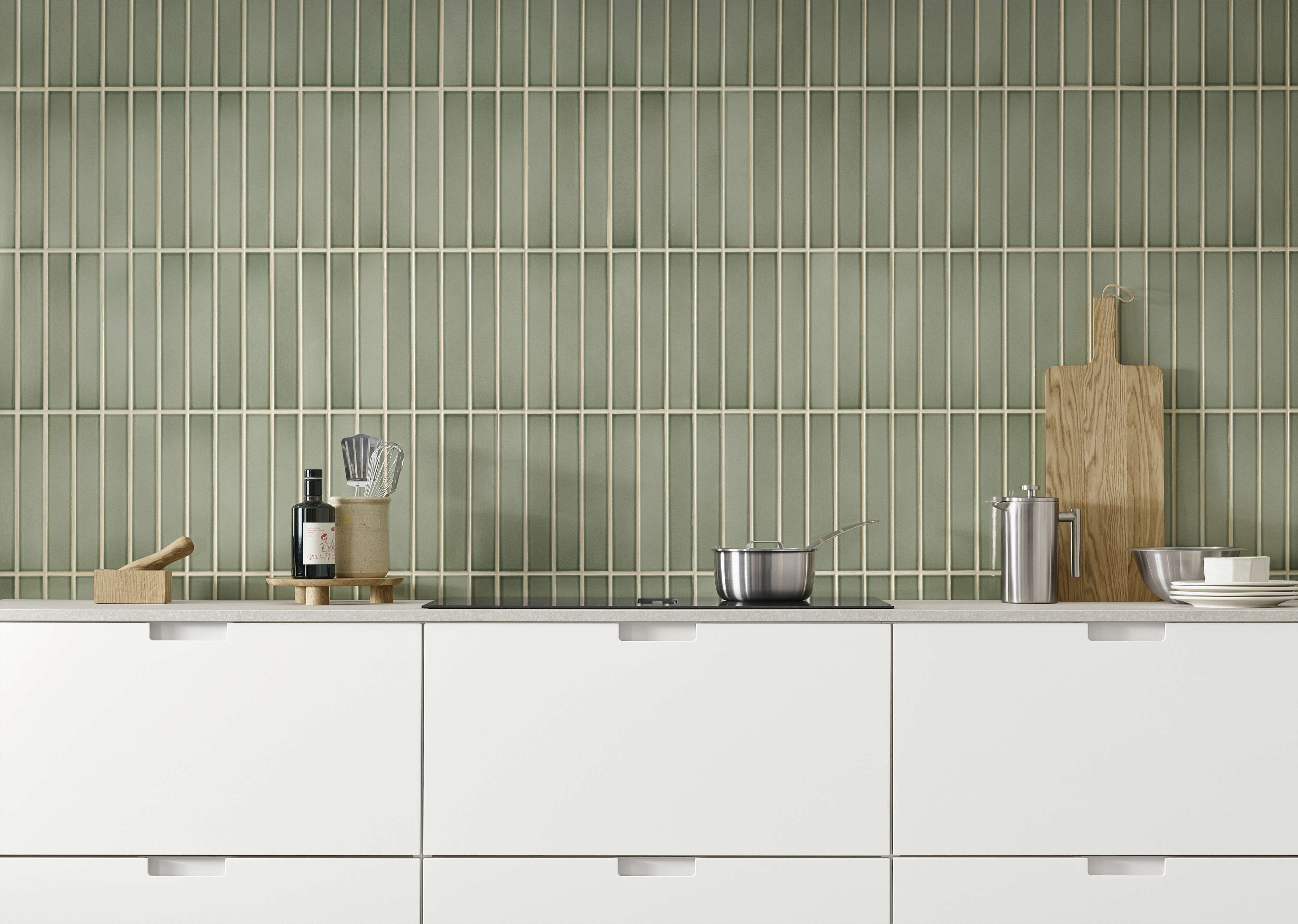 EVENTO white kitchen with sleek drawers against a modern green tiled wall, combining minimalistic design with functional elegance.