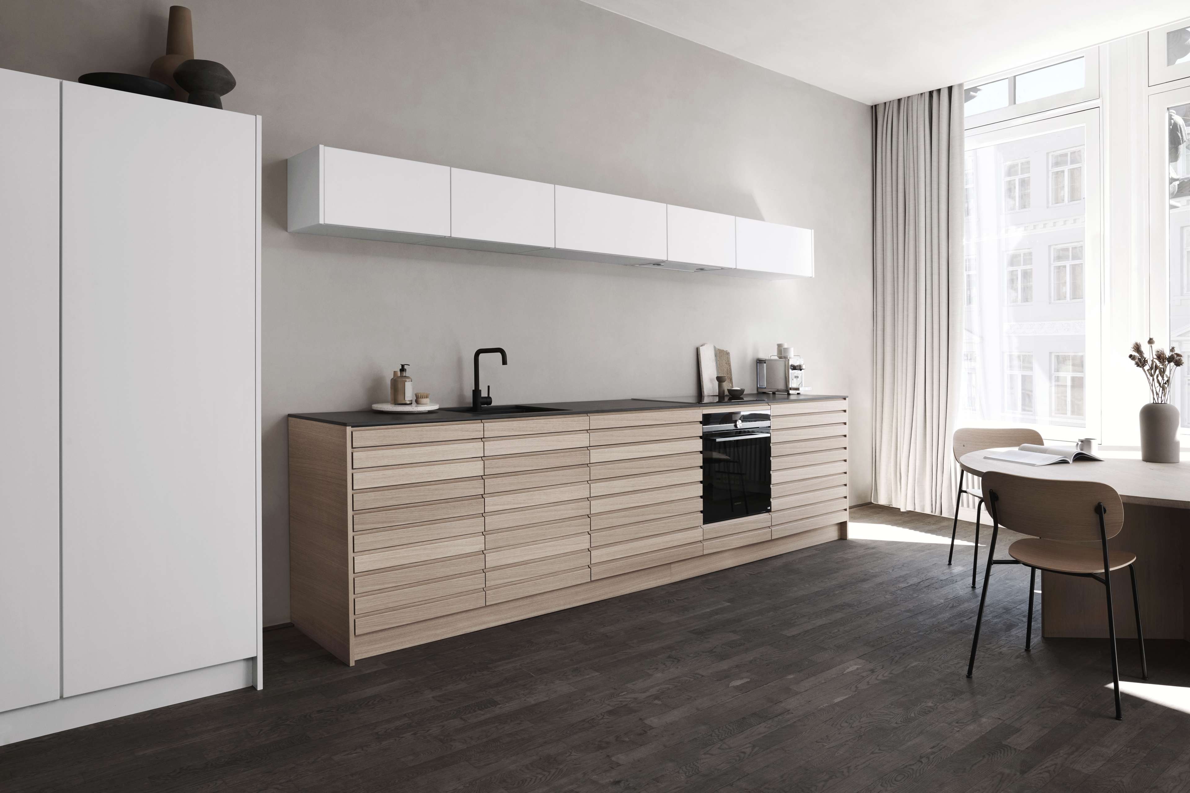 CIMA-Küche aus heller Eiche mit eleganten Schränken mit horizontaler Maserung und minimalistischen weißen Akzenten, die einen modernen und eleganten Raum für kulinarische Kreativität schaffen.