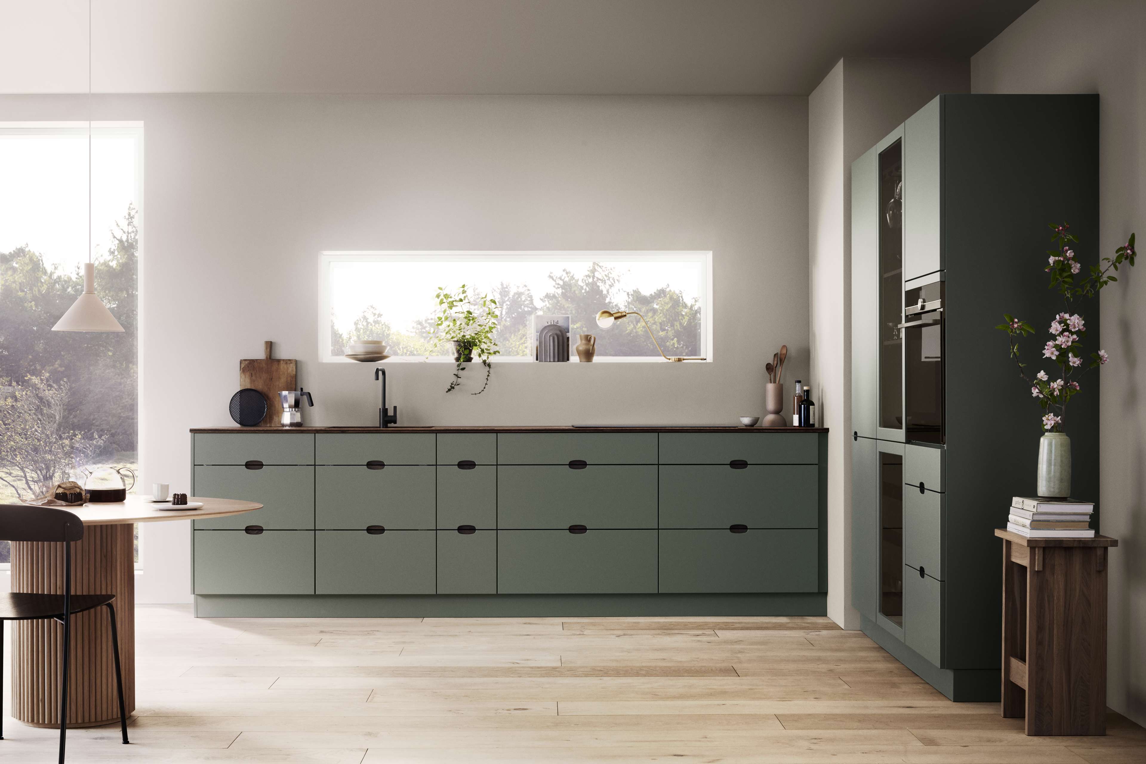 Green kitchen with integrated handles and a wooden worktop