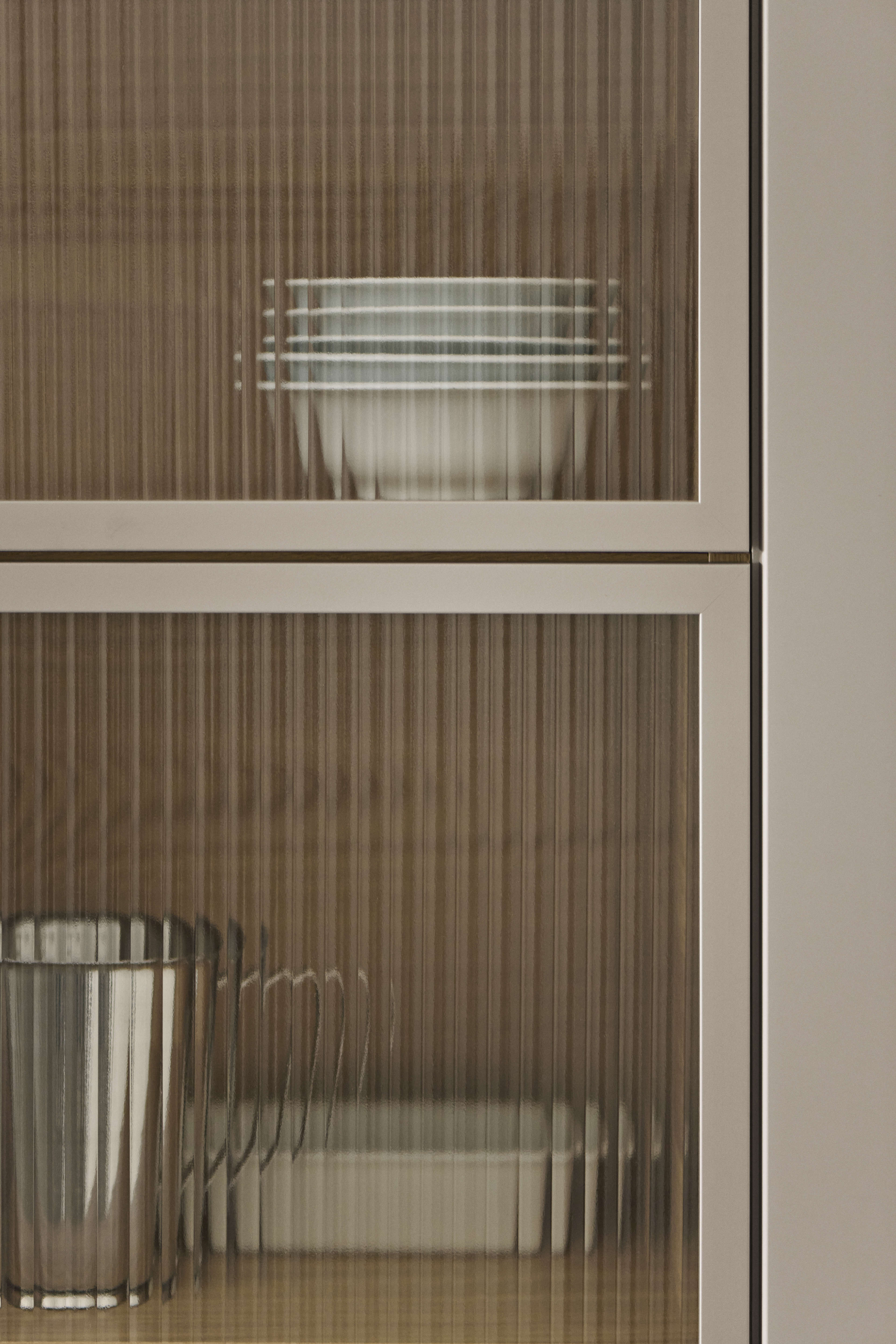 EVENTO arizona beige kitchen cabinet with vertical glass doors and textured finish, offering a sophisticated and organized storage solution.