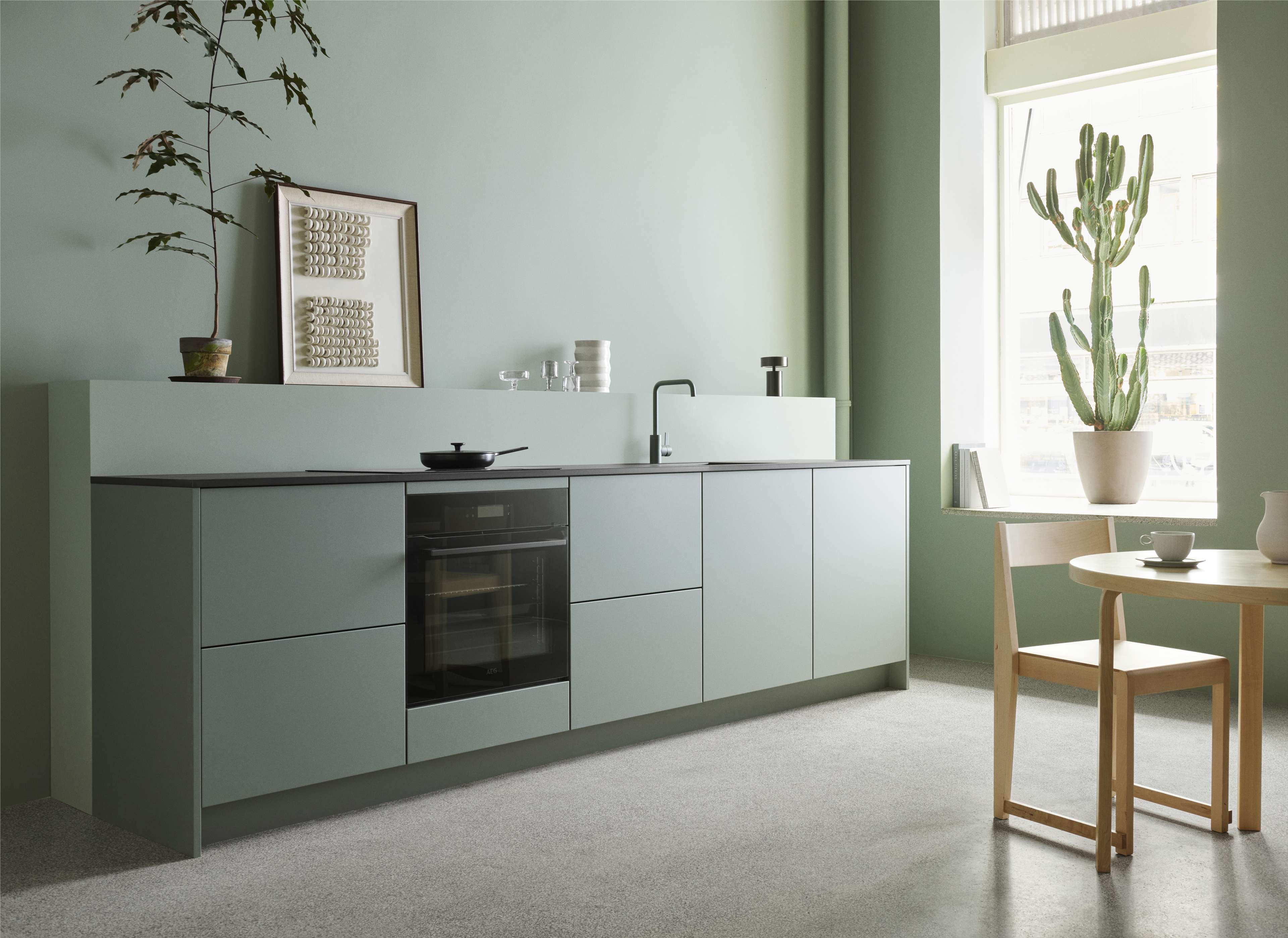 VEDA Touch green kitchen featuring minimalist flat-panel cabinets, seamlessly blending with the modern interior and soft ambient natural light.