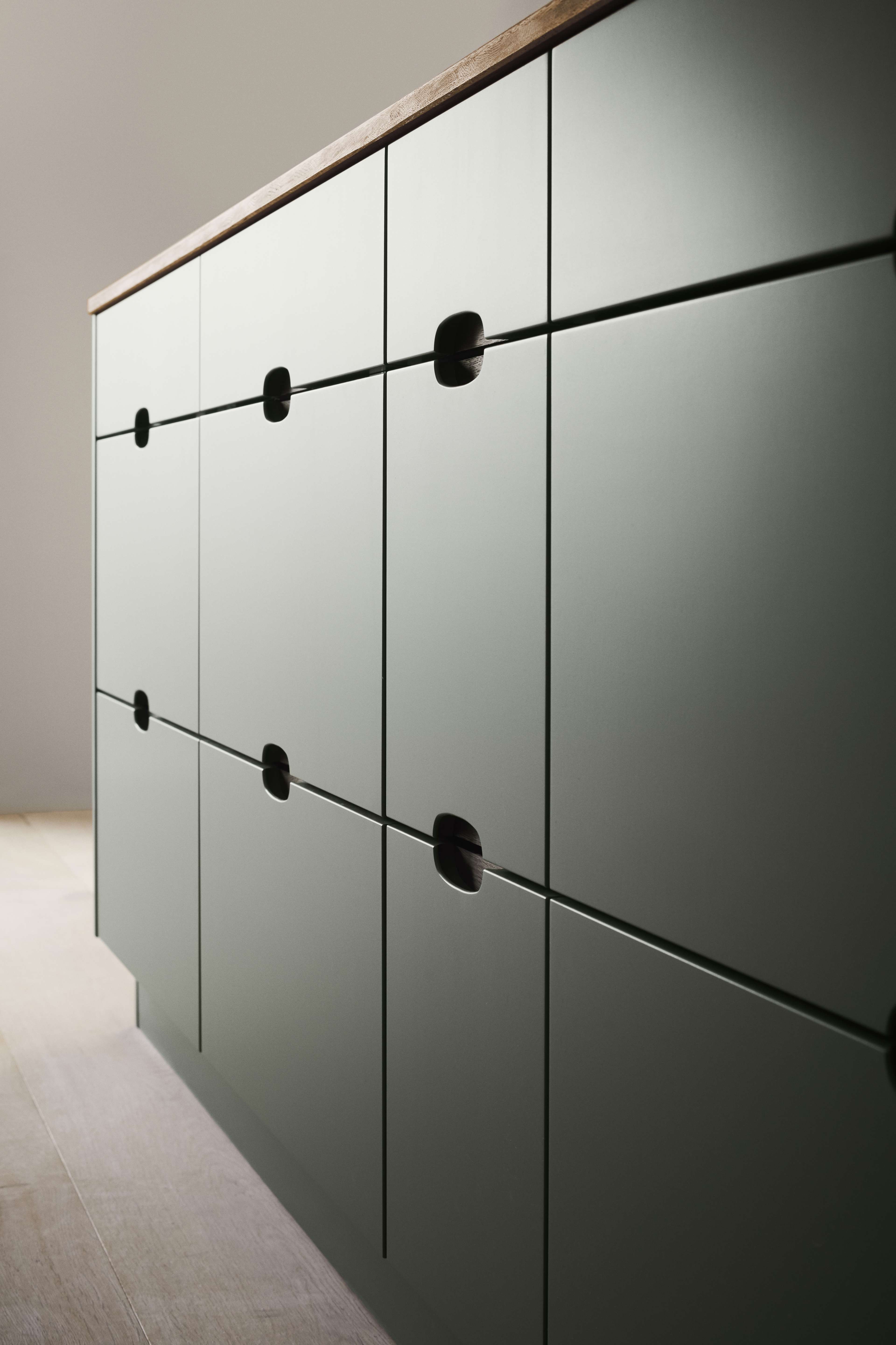 Green fronts with integrated handles and a wooden worktop