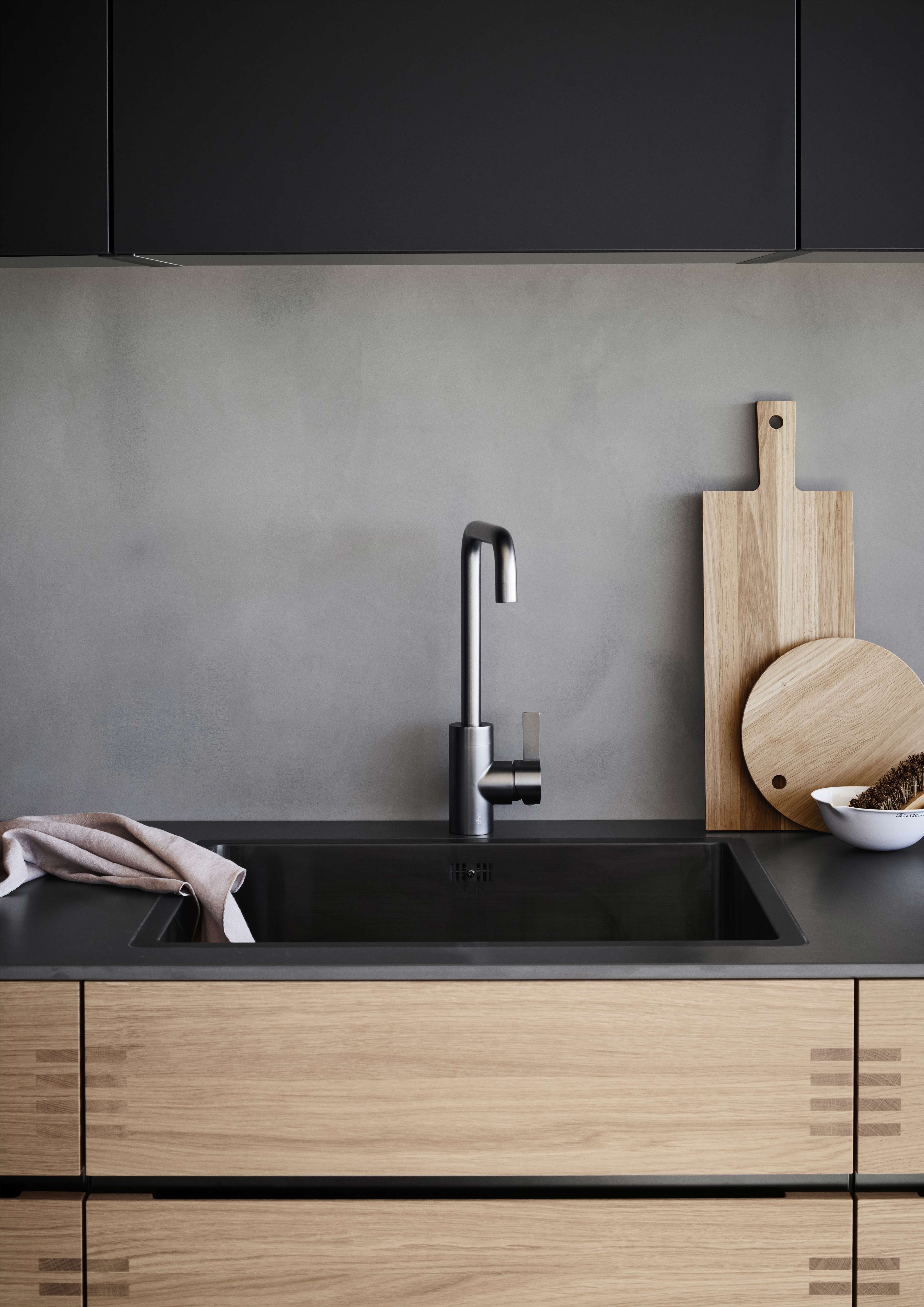 OAKWOOD houten keuken met strakke zwarte werkbladen en matzwarte kraan, moderne stijl met natuurlijke houtnerfdetails voor een warme esthetiek.