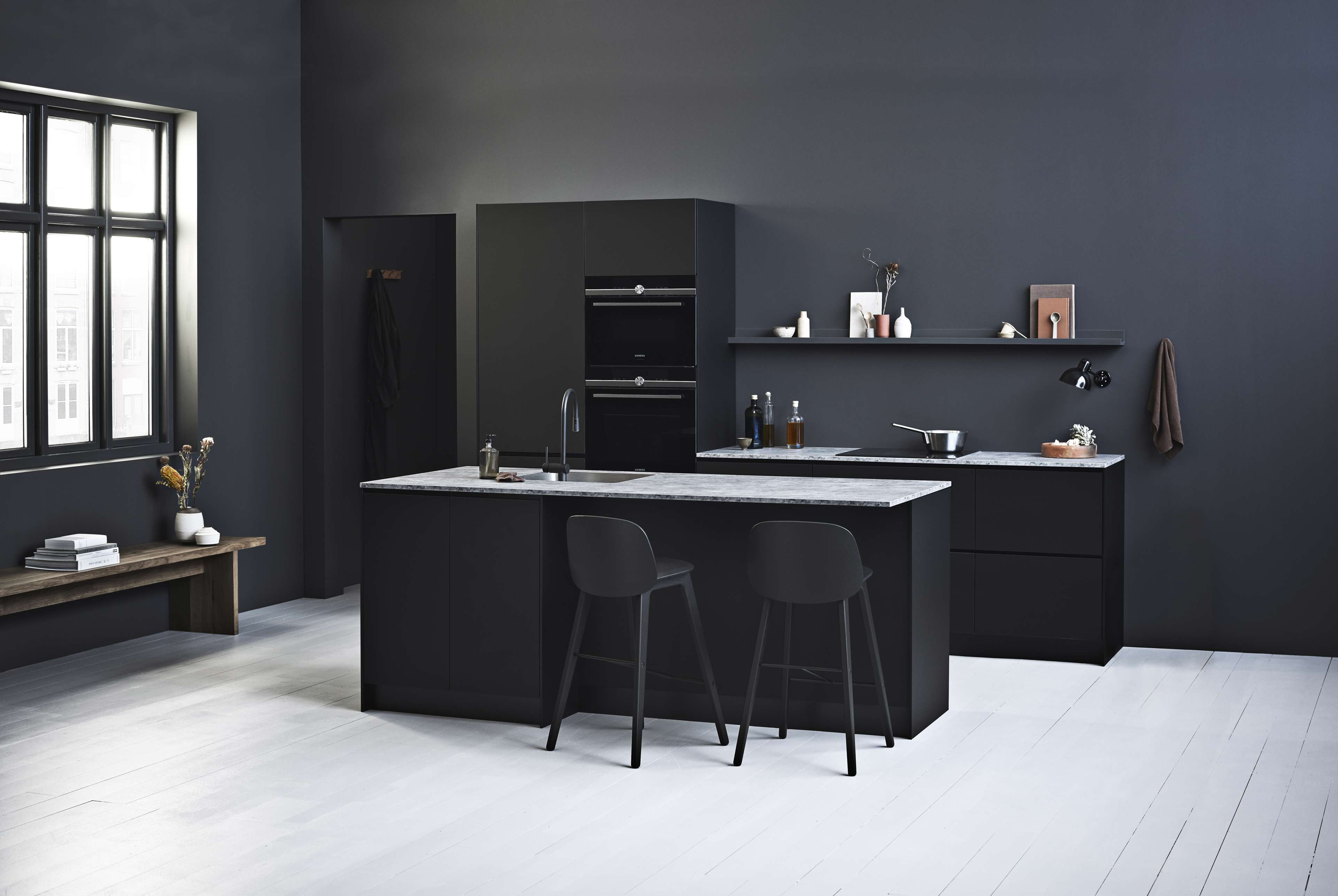 PRATO svart modernt kök med eleganta skåp och minimalistisk design, med en central ö och integrerad ugn, som blandar elegans och funktion.