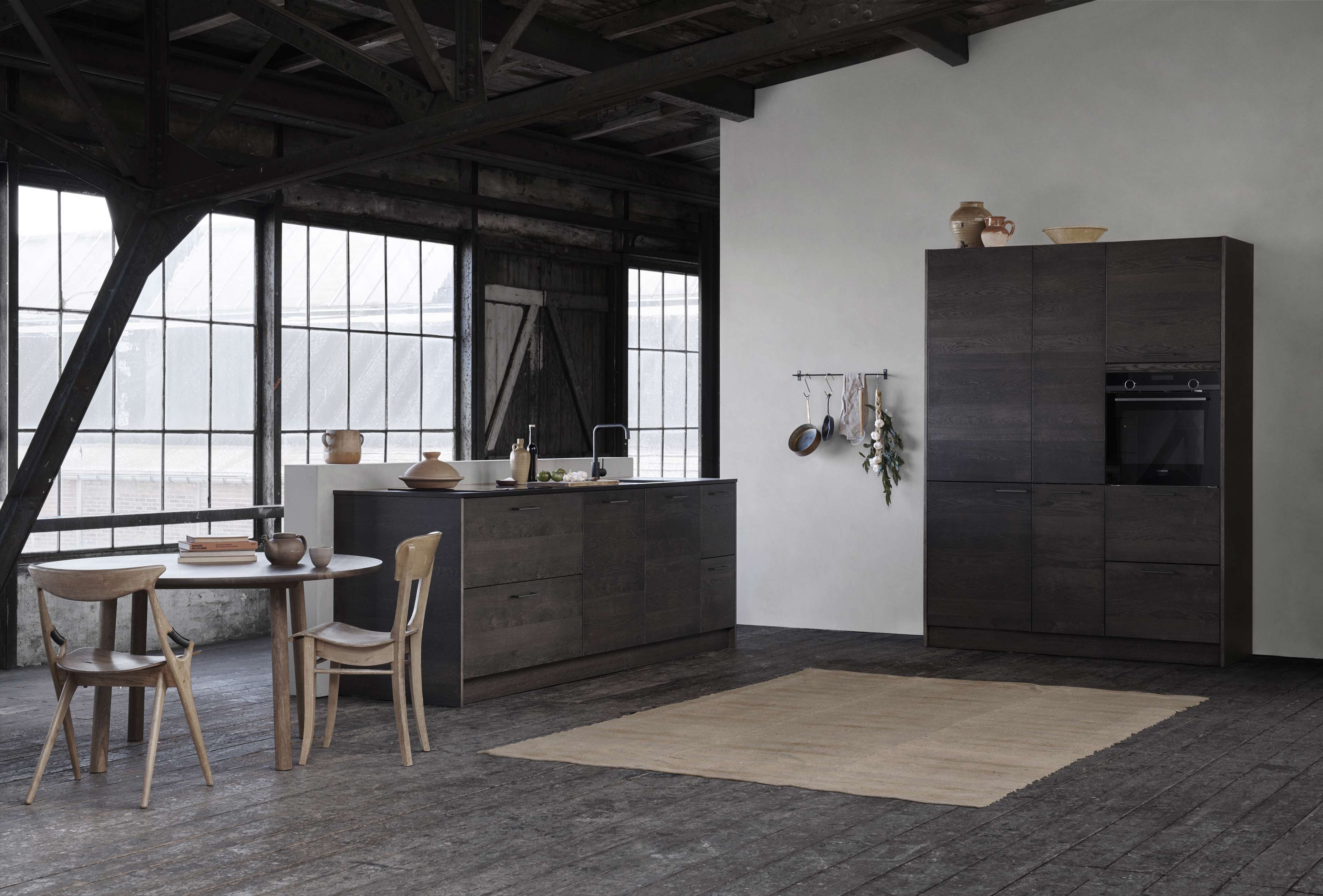 VEDA mørk eikekjøkken med elegante skap og øy med minimalistisk design i en moderne, industriell stil for et raffinert kulinarisk rom.