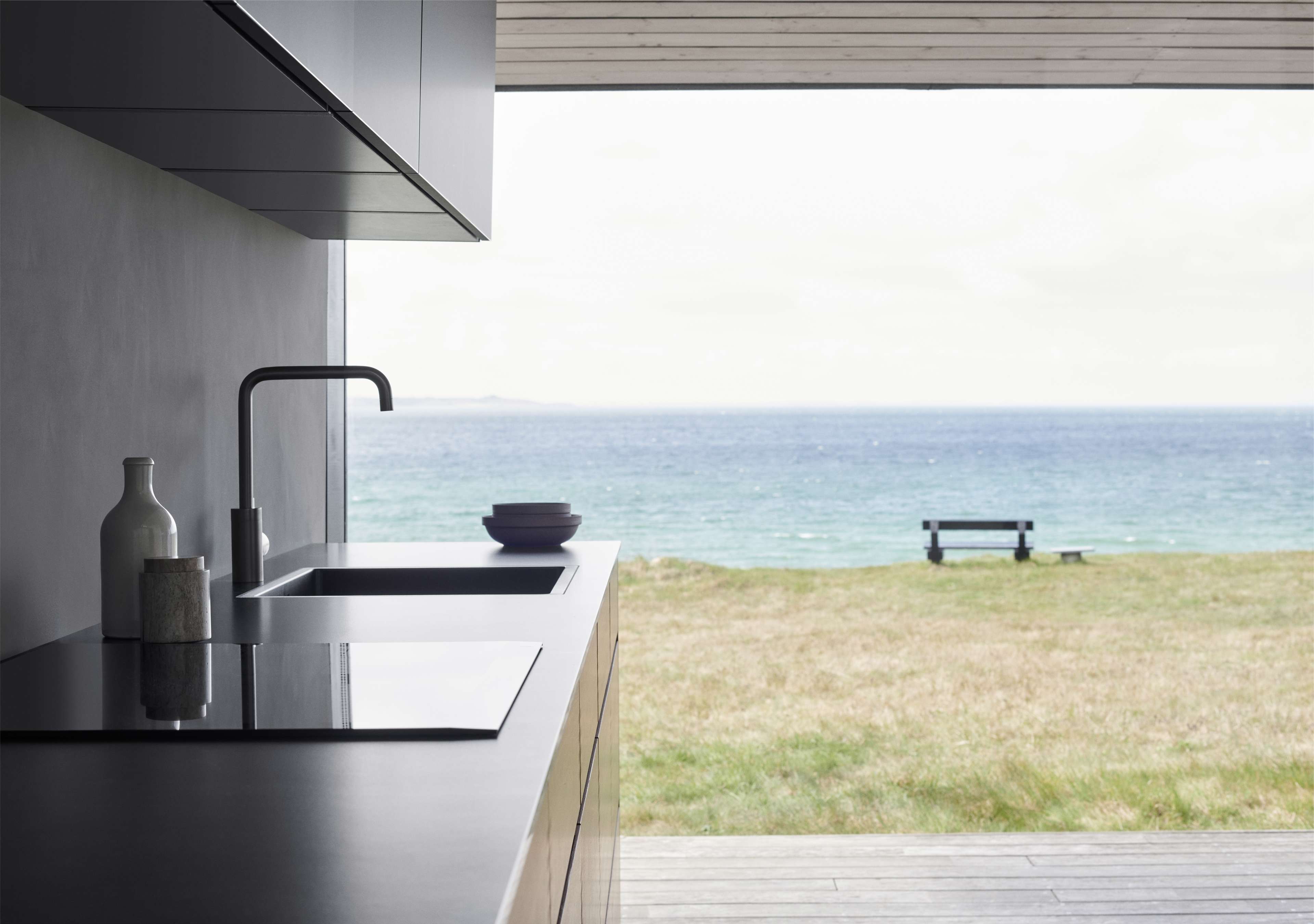OAKWOOD Trækøkken med et minimalistisk design med slanke skabe og mørke bordplader, der blander funktionalitet med en moderne kystudsigt.