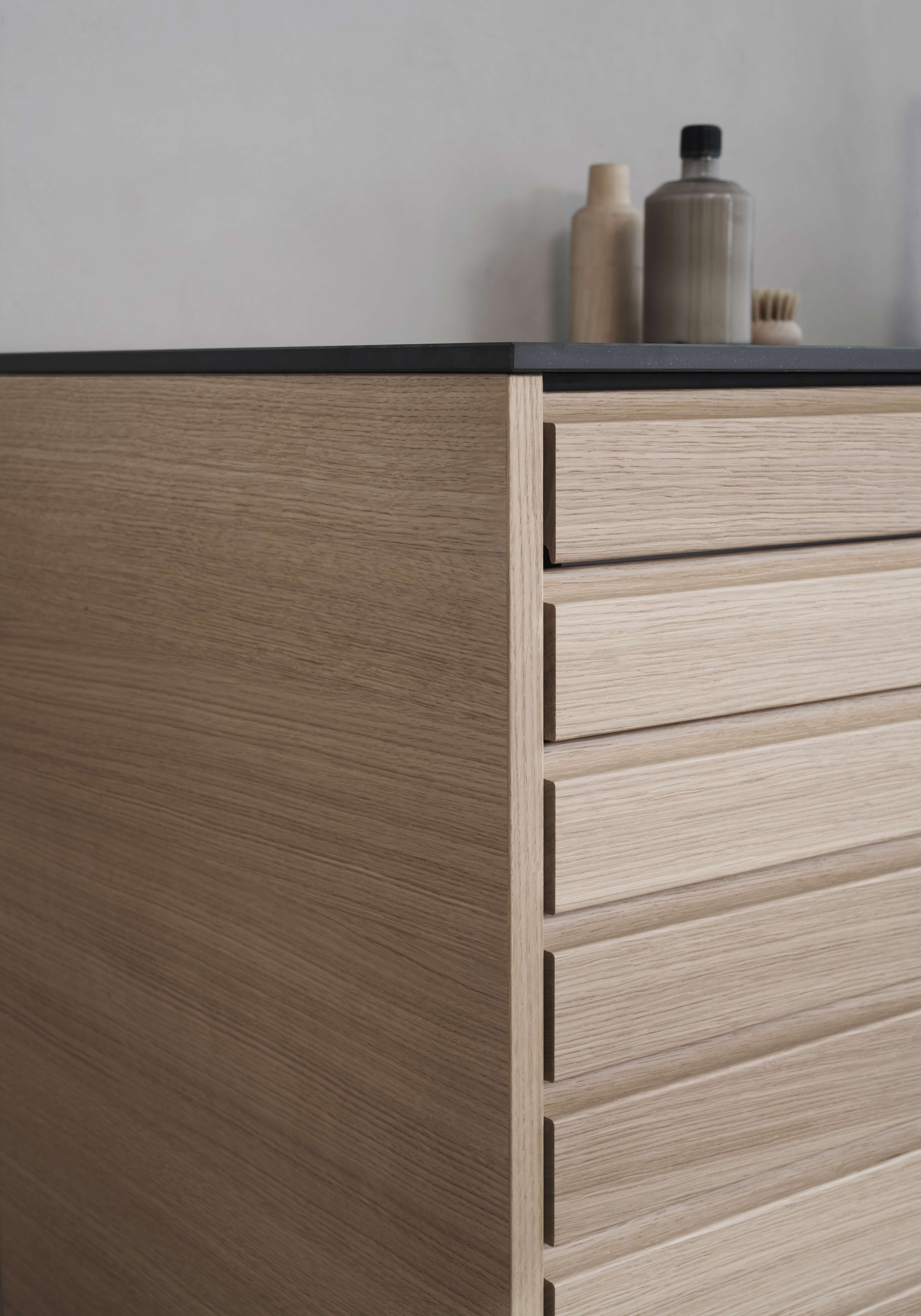 CIMA kökslådor i ljus ek som visar eleganta horisontella lameller och erbjuder en modern och minimalistisk estetik med varma trätoner.