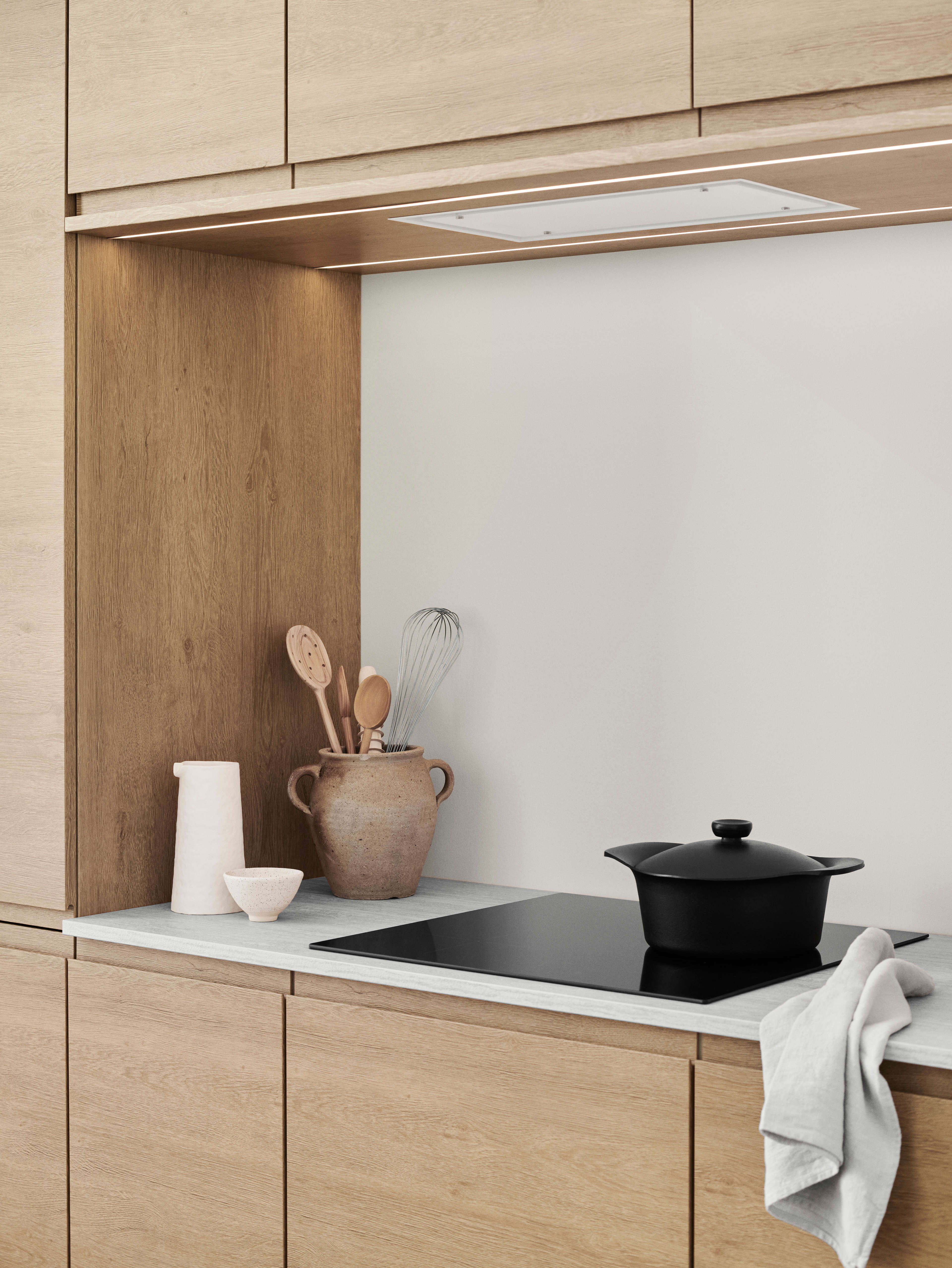 NOLIAM trekjøkken med lyse eikeskap, med minimalistisk design og integrert LED-belysning for en elegant og moderne kokeplass.