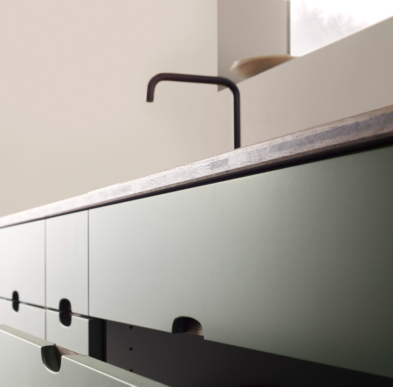 Green kitchen with a wooden worktop and a black faucet