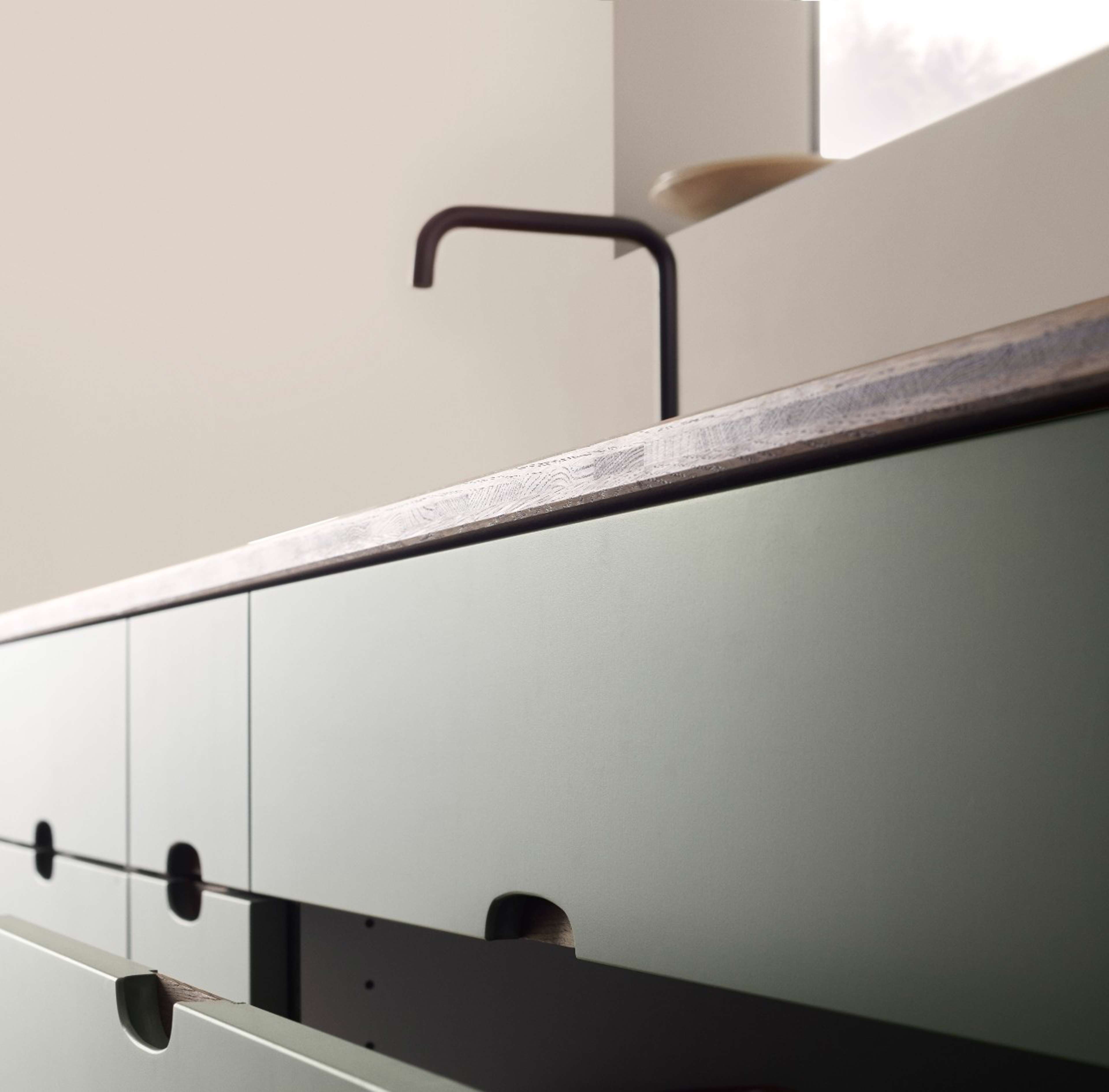 Green kitchen with a wooden worktop and a black faucet