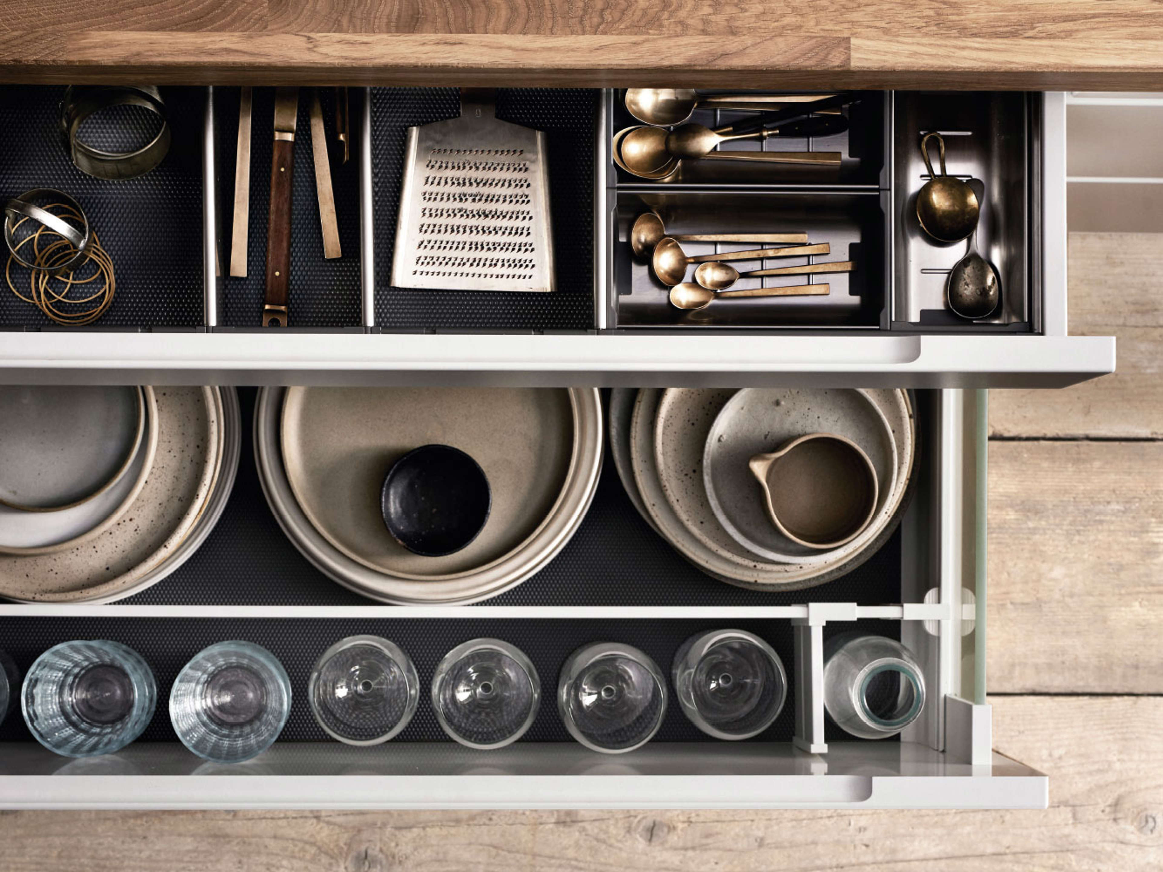 MANO white kitchen drawer organizer with oak countertop, showcasing minimalist Scandinavian design and efficient storage solutions for utensils and dishware.