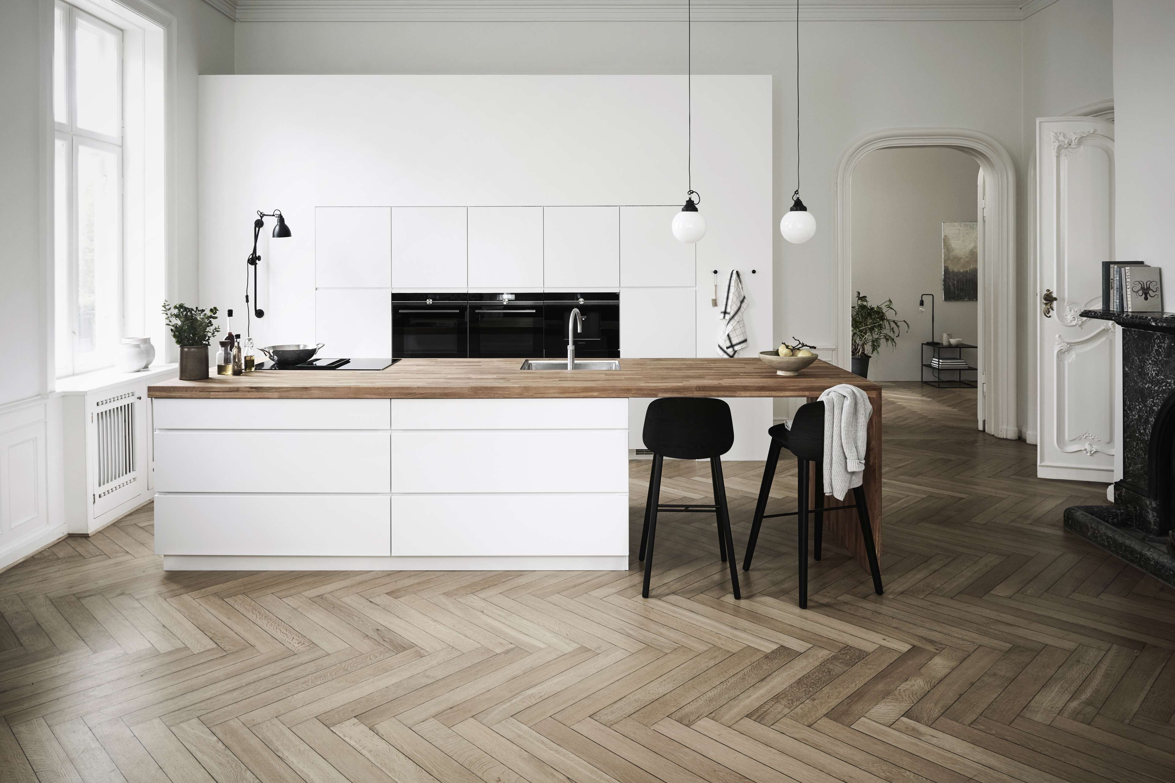 Cocina blanca con isla de cocina y una encimera de madera maciza