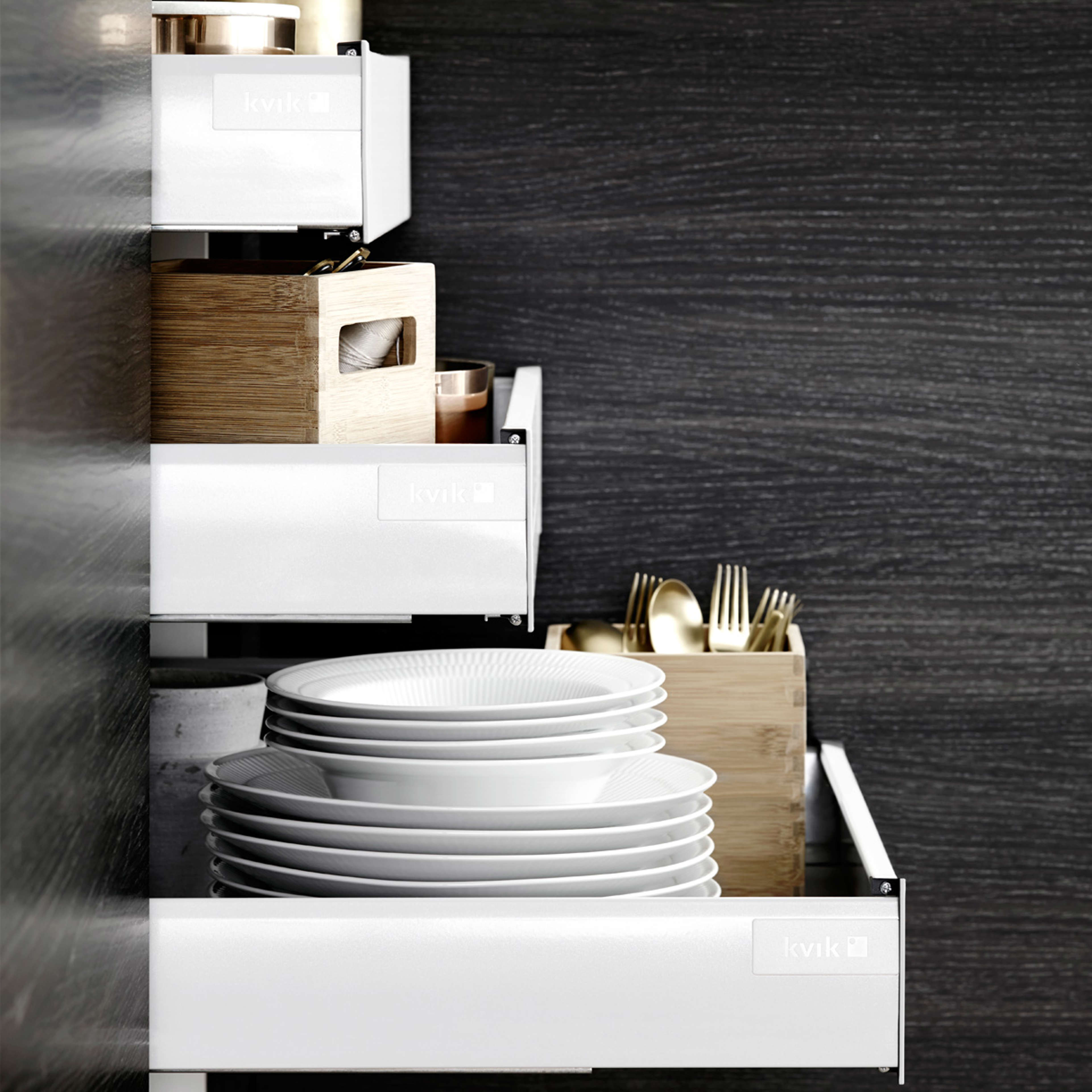 MANO sera køkkenet har slanke hvide skuffer med et minimalistisk design, der komplementerer den mørke panelbaggrund for et moderne, elegant look.