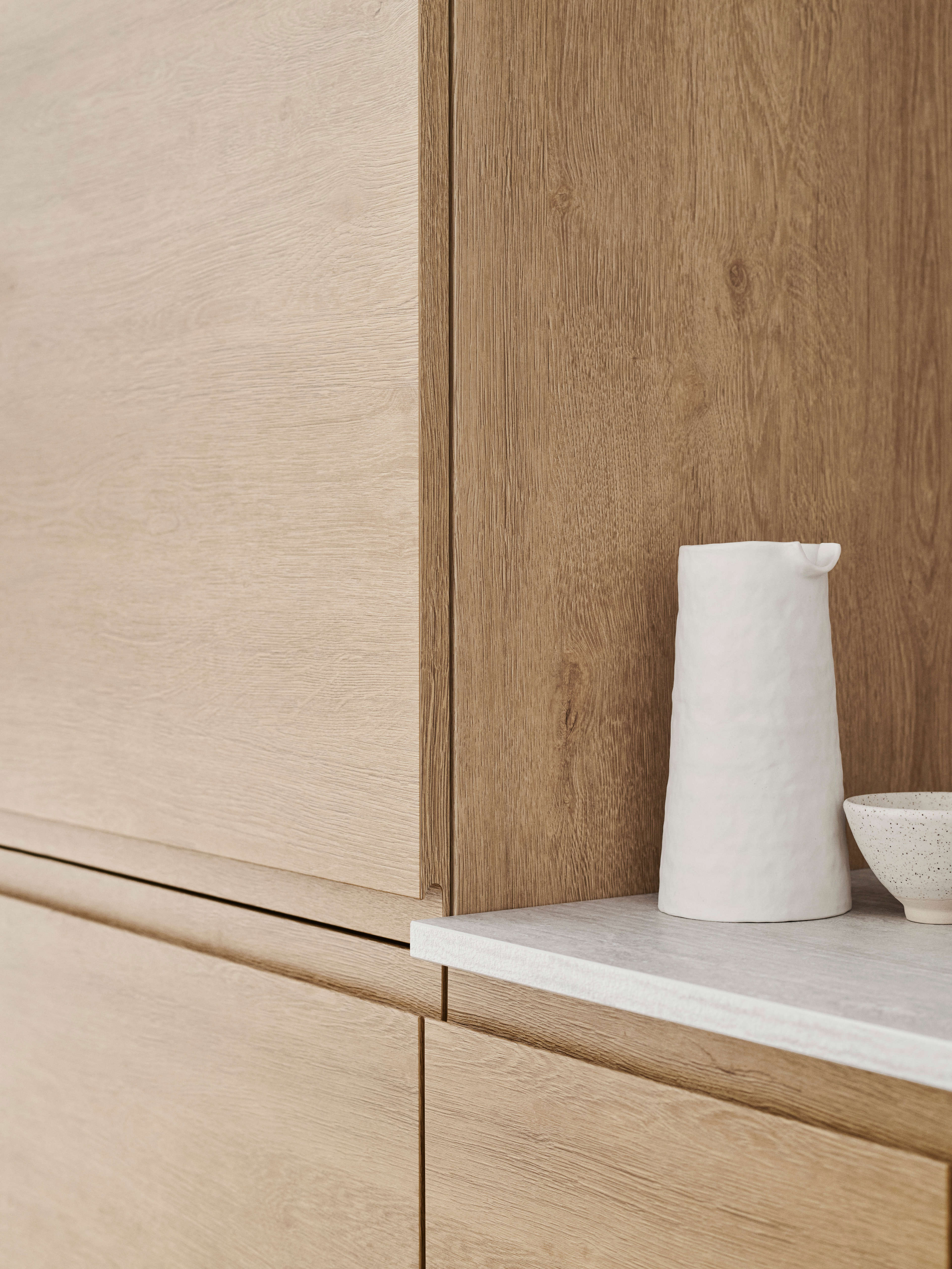 Stilig NOLIAM-kjøkkenskap i tre med lys eikefinish, som viser sømløs moderne design for et varmt og innbydende kulinarisk rom.
