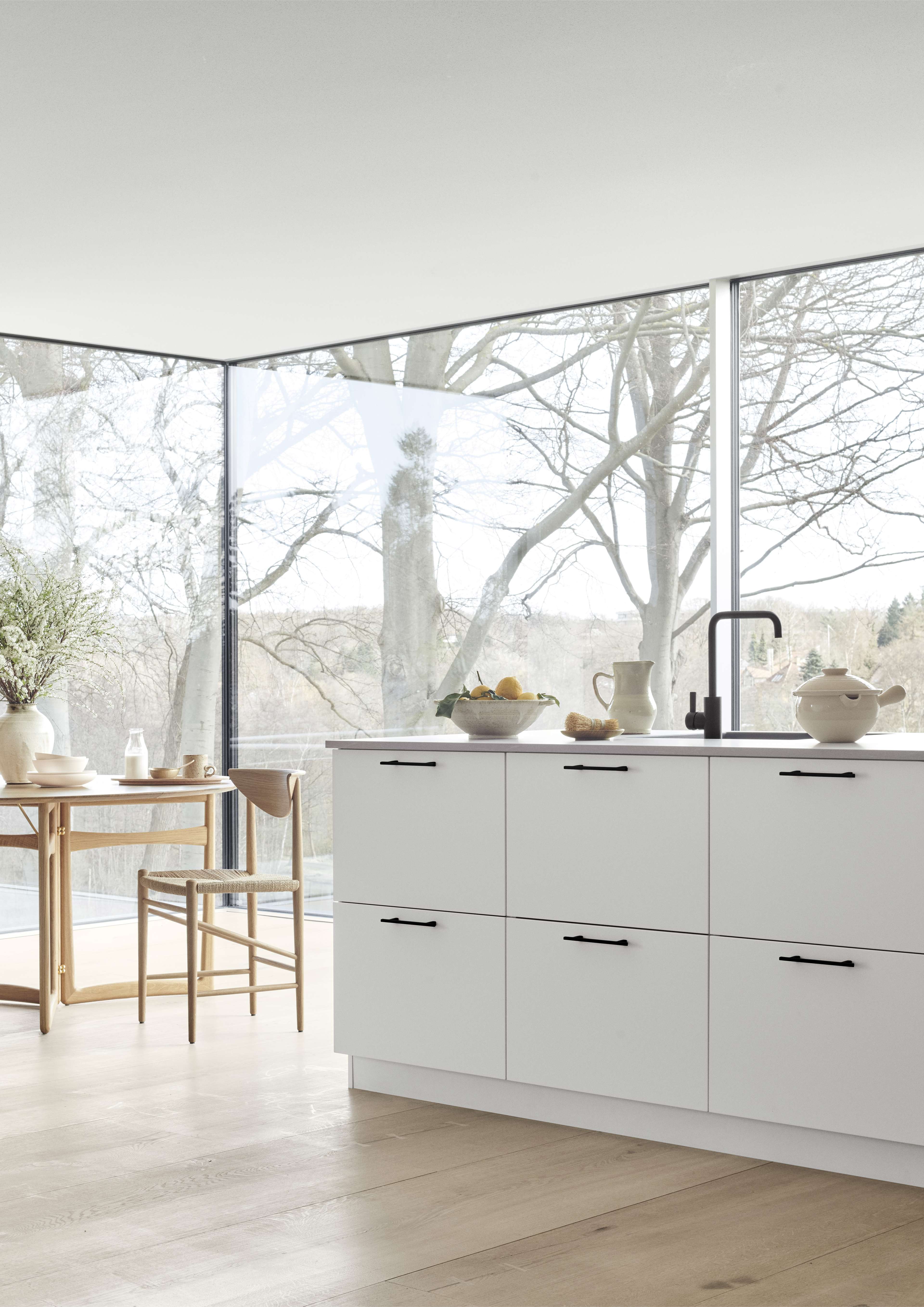 VEDA white kitchen cabinets with minimalist black handles, embodying sleek modern design, creating a bright and spacious culinary environment.