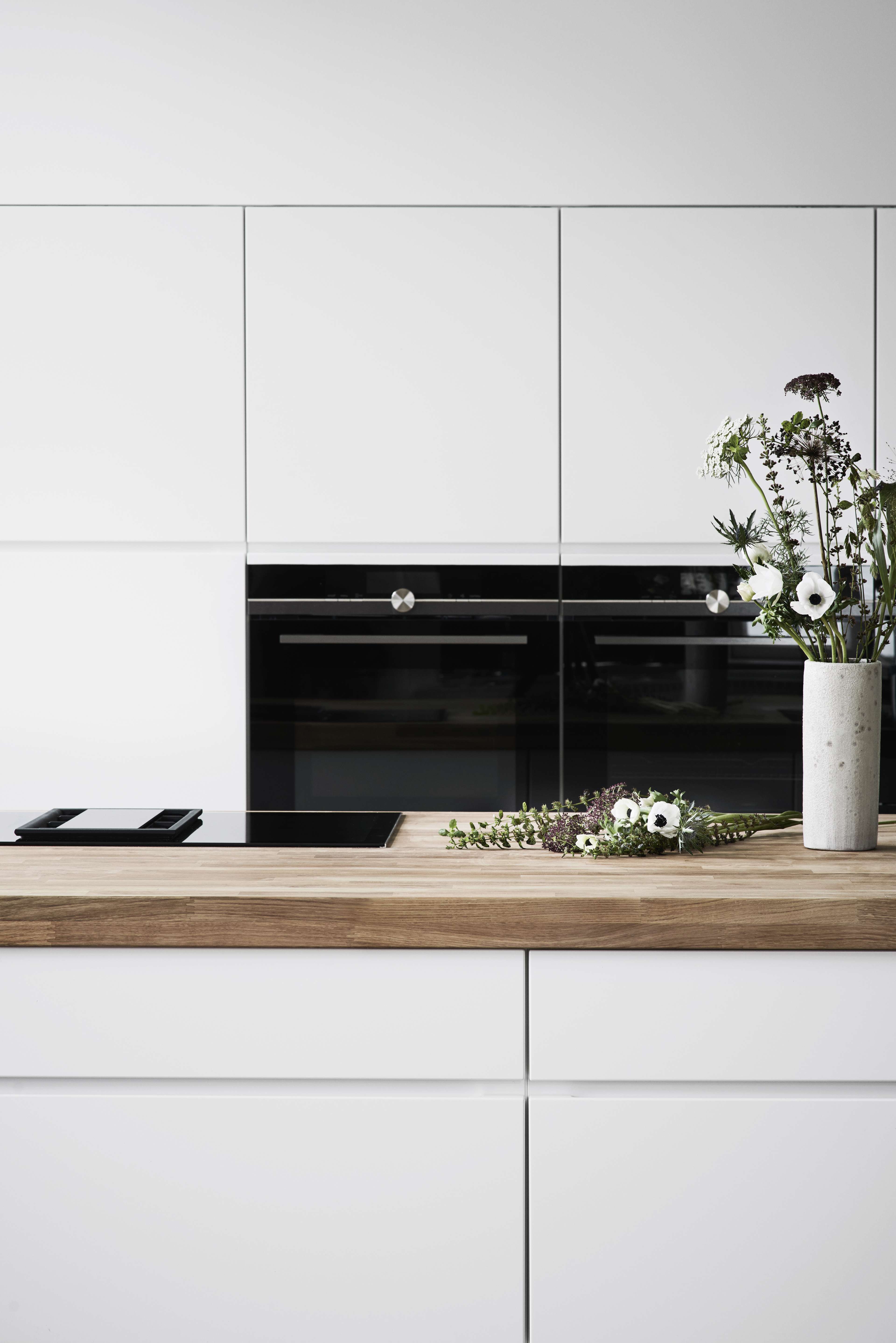 Cuisine blanche avec un plan de travail en bois massif et des appareils électroménagers intégrés.