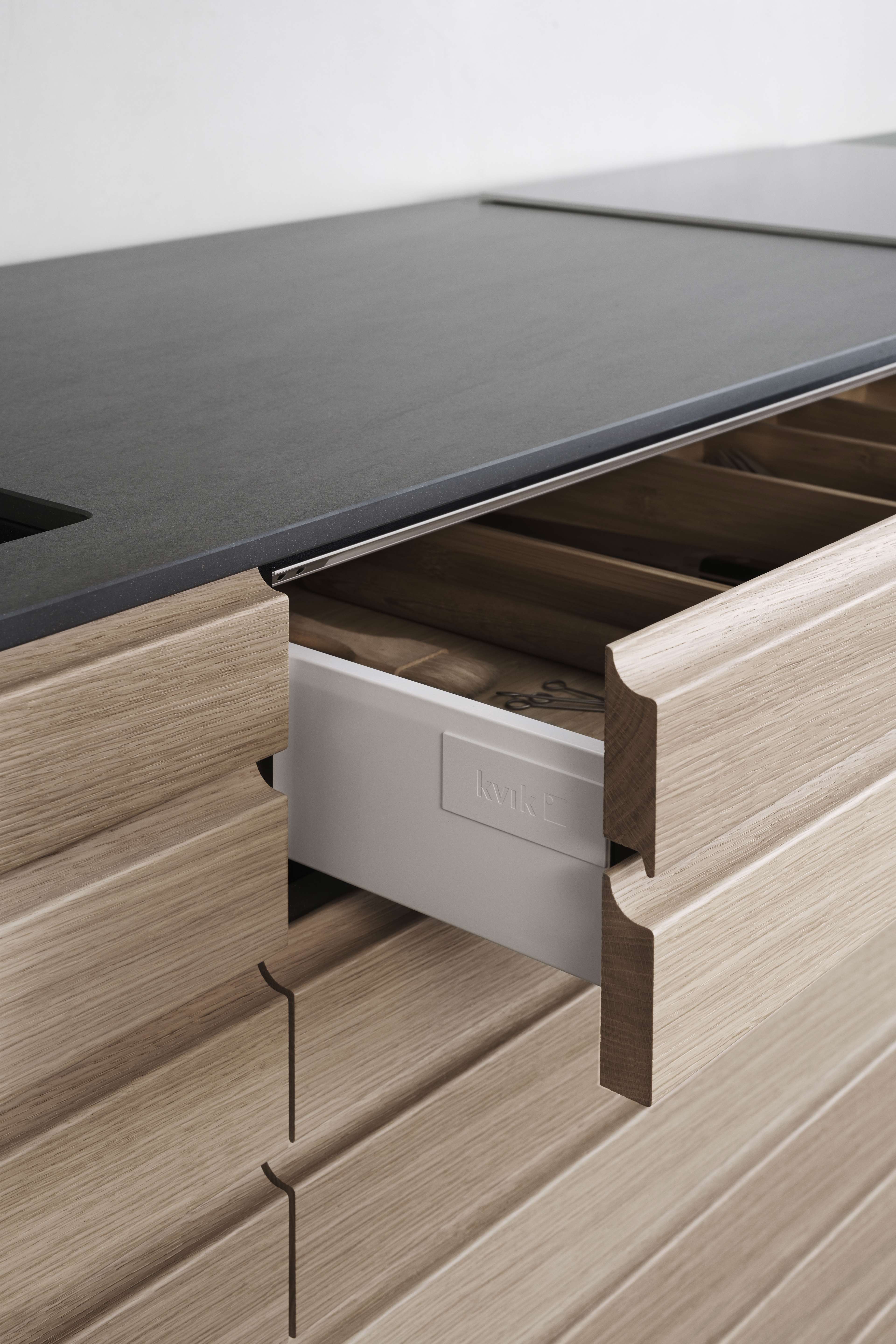CIMA light oak kitchen drawer with clean lines, featuring a sleek black countertop, perfect for a modern, minimalist, and organized kitchen space.